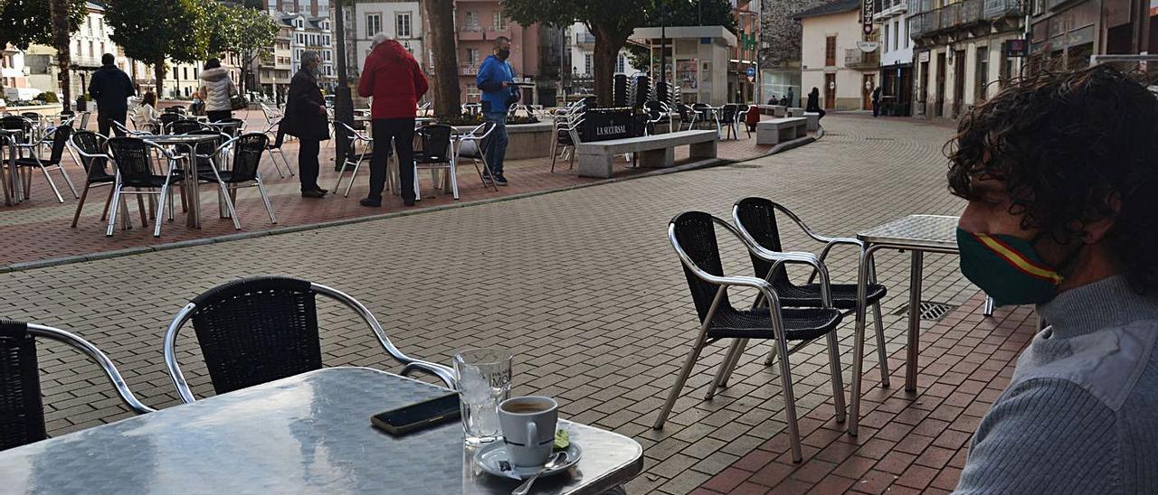 Alfonso Alberto Baliela toma un café en la plaza del centro de Luarca, con las terrazas semivacías. | A. M. Serrano