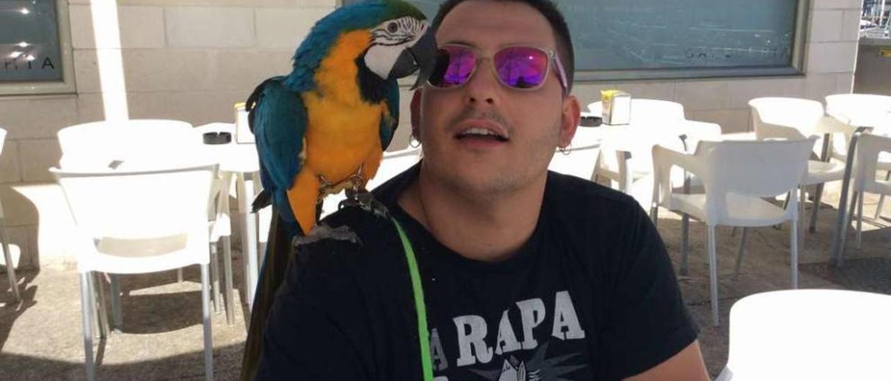 Hugo Olivera con su loro guacamayo &quot;Perla&quot; al hombro en una terraza de Cangas. // FDV