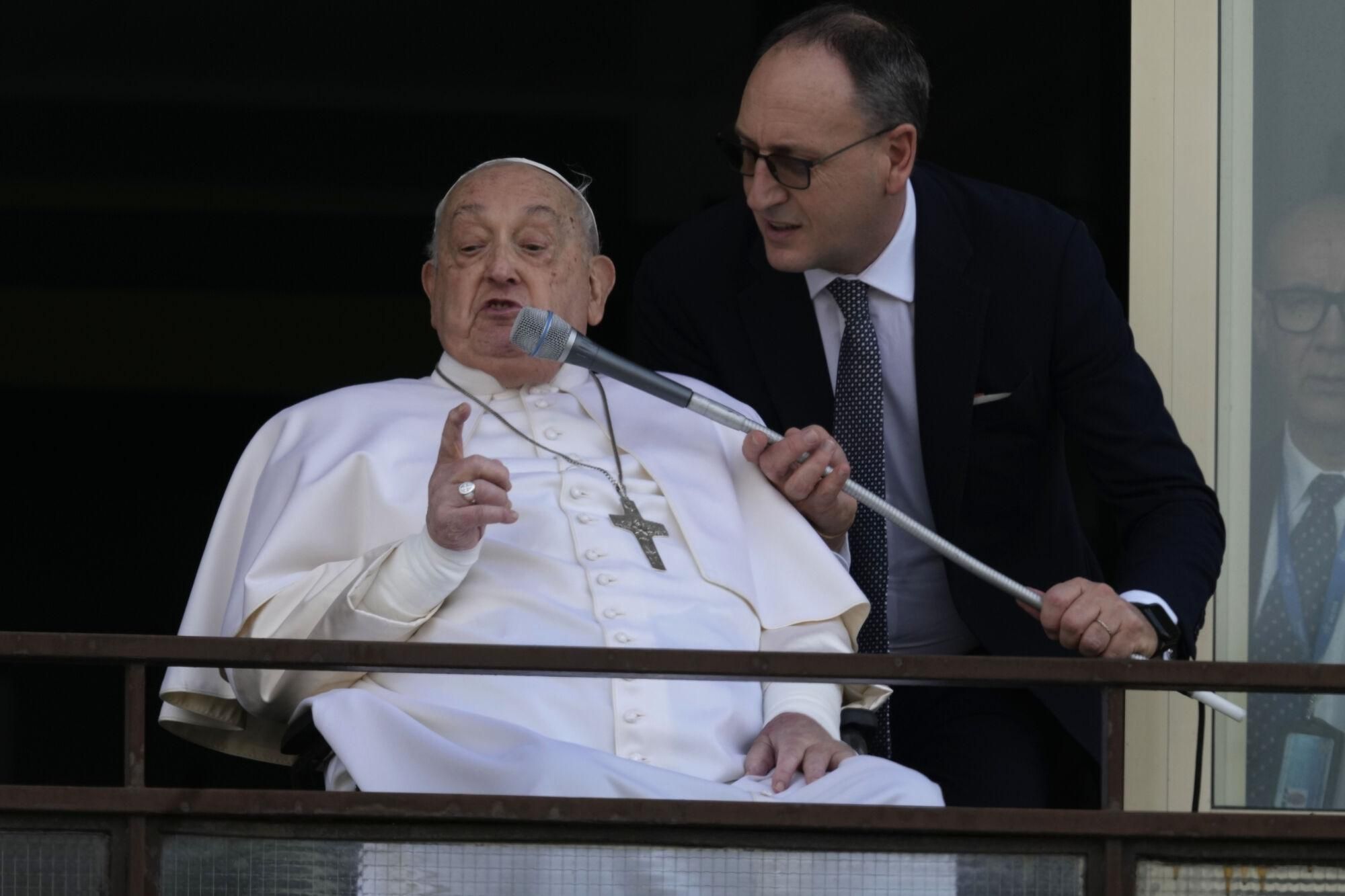 Pope Francis talks on a microphone as he appears at a window of the Agostino Gemelli Polyclinic in Rome, Sunday, March 23, 2025, where he has been treated for bronchitis and bilateral pneumonia since Feb. 14. (AP Photo/Domenico Stinellis). EDITORIAL USE ONLY/ONLY ITALY AND SPAIN