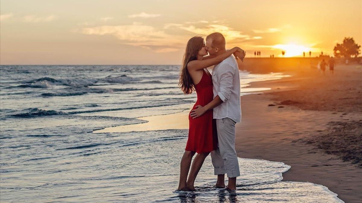 Una pareja besándose en la playa, la típica estampa del amor veraniego.