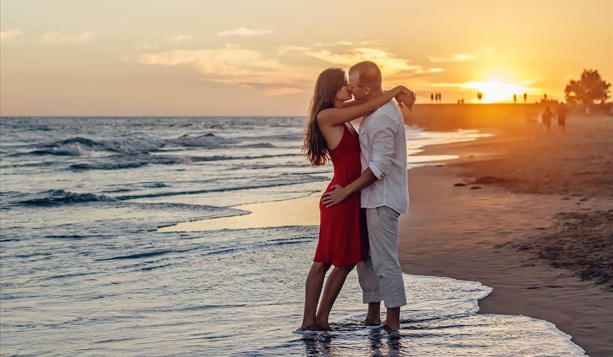 Una pareja besándose en la playa, la típica estampa del amor veraniego. 