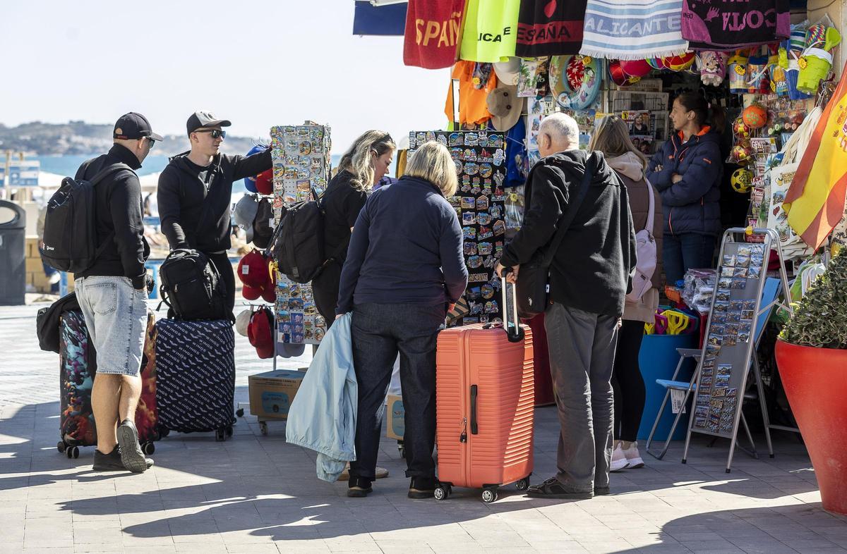 Turistas con sus maletas haciendo compras en Alicante.