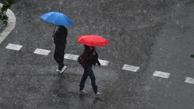 Dues persones passegen sota la pluja.