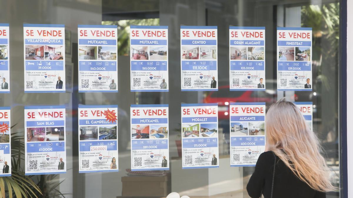 Una posible compradora mira el escaparate de una inmobiliaria en Alicante.
