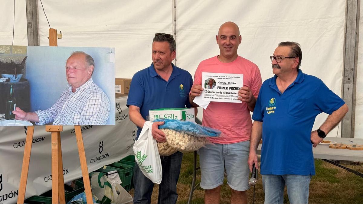 Miguel Cuesta, yerno de Manuel Tuero, recibe el primer premio del concurso de manos de Samuel González y José Manuel Álvarez, miembros de la organización, junto a una imagen de Manolo "Los Piñares".