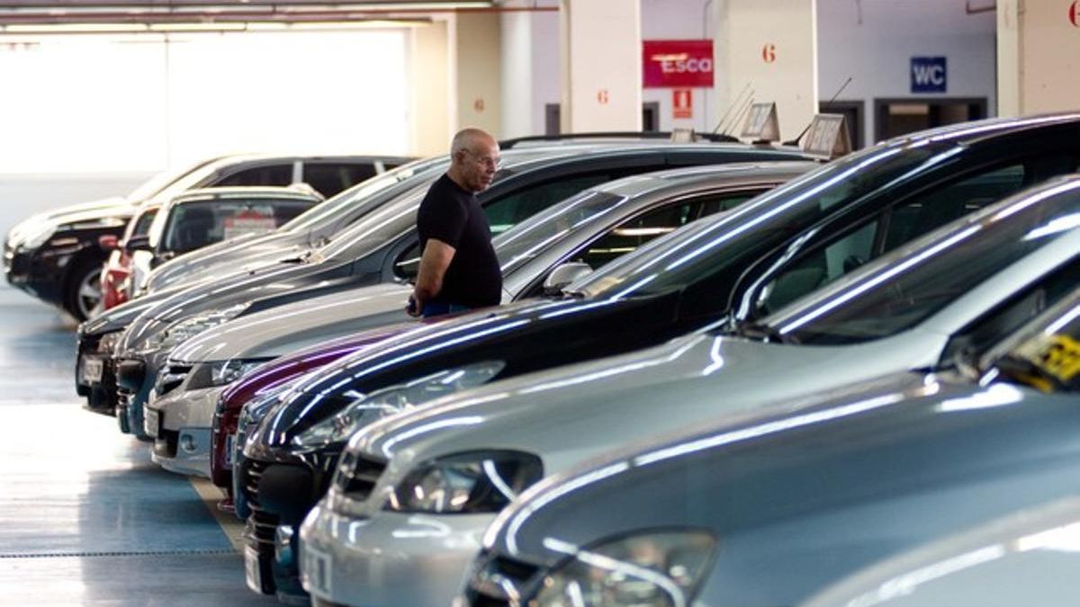 Un hombre mira vehículos en un concesionario de coches.