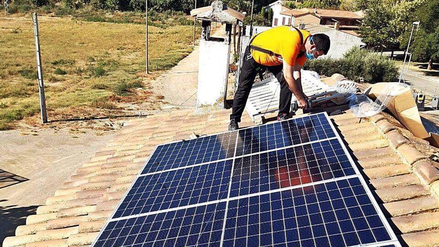 Un operari instal·lant una placa solar a la teulada d&#039;un habitatge