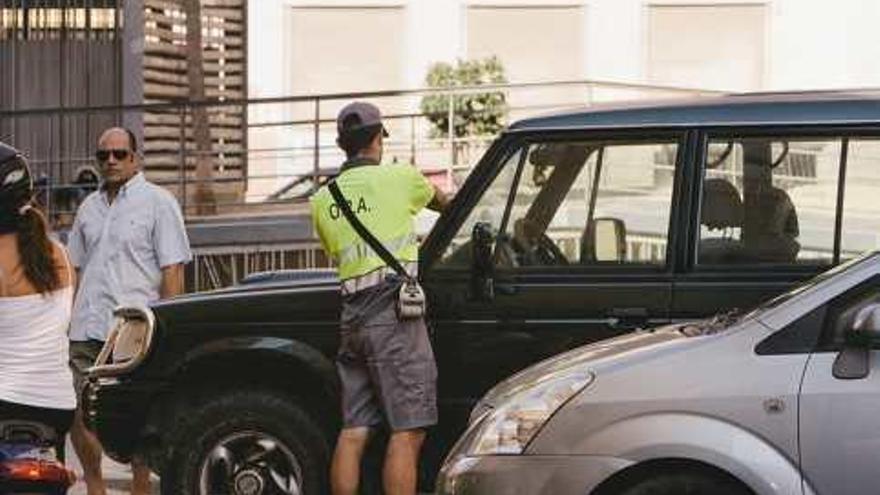 Un operario del servicio pone una multa a un vehículo sin ticket.