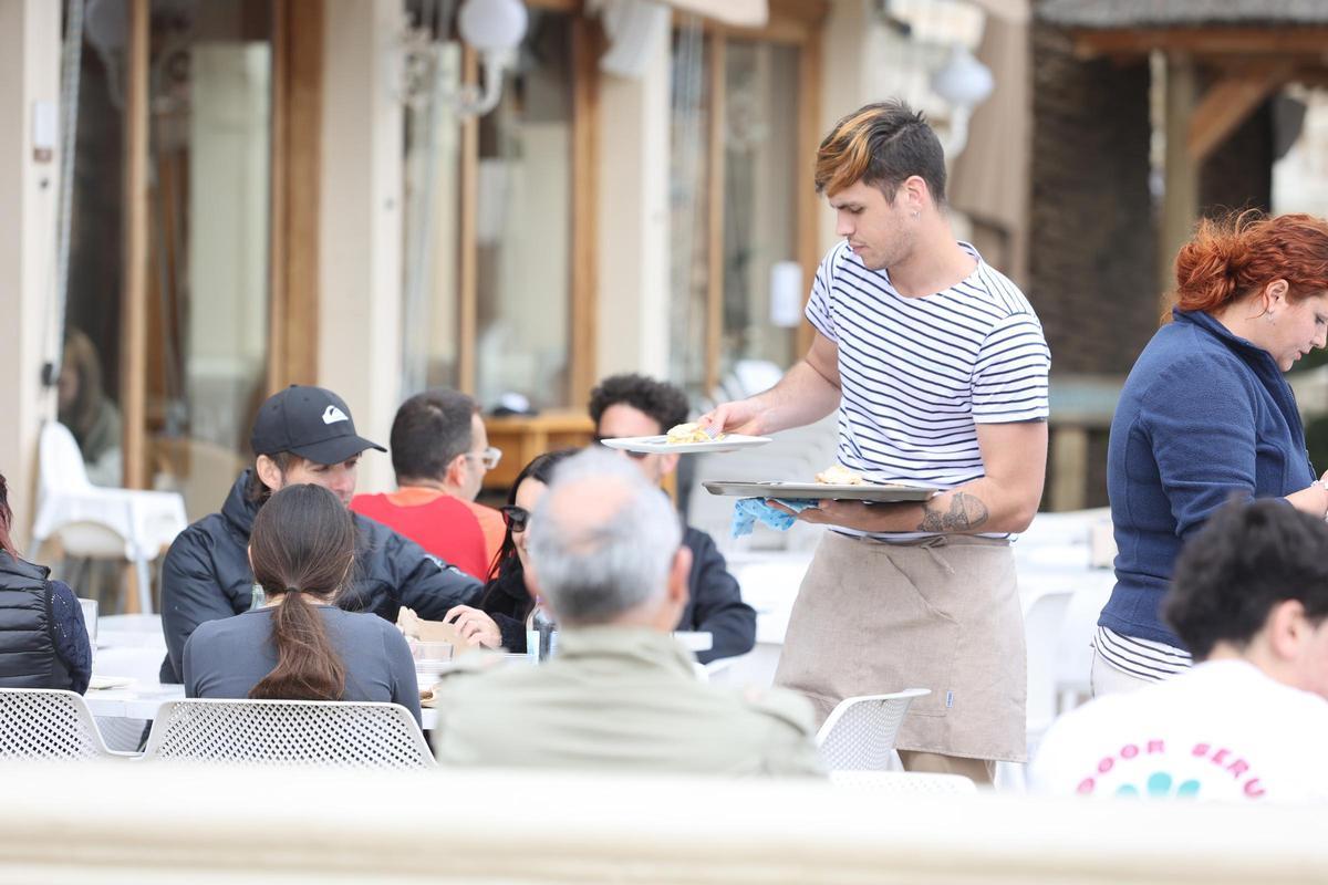 Un camarero sirve unas mesas en un restaurante de Benicàssim.