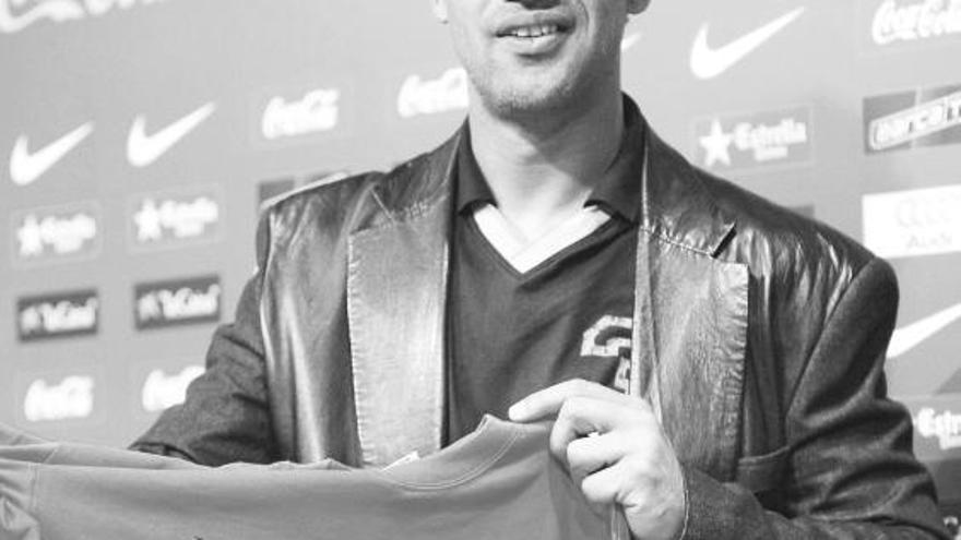Rijkaard muestra la camiseta que le regalaron los periodistas que siguen al Barça.