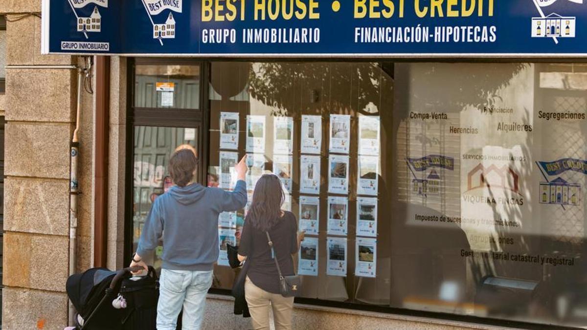 Una pareja observa el escaparate de una inmobiliaria en Santiago