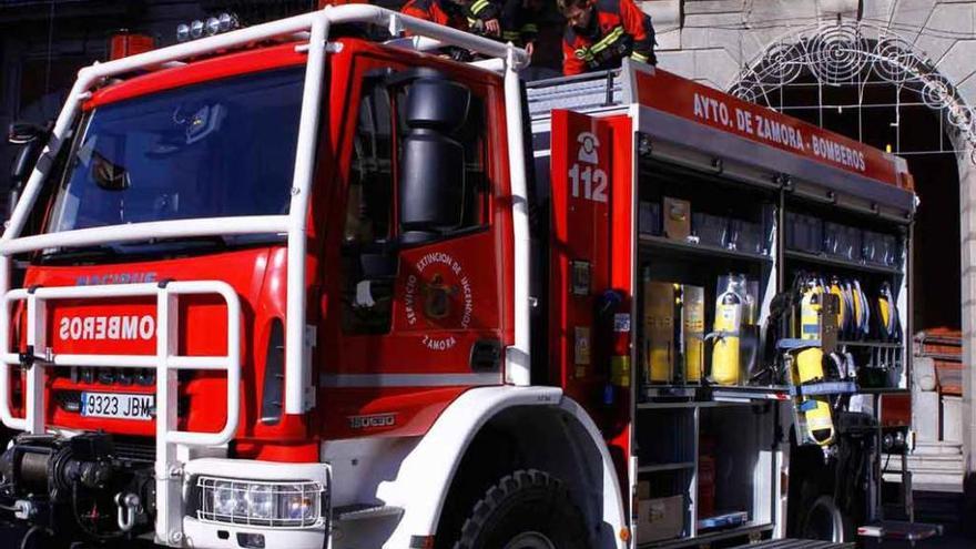 Tres efectivos de bomberos municipales sobre uno de los camiones del parque.