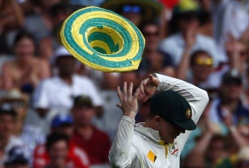 A hat that blew onto the field, is blown off the head of Australia's Rogers after he put it on during the first day of the fourth Ashes cricket test against England, at the Melbourne cricket ground