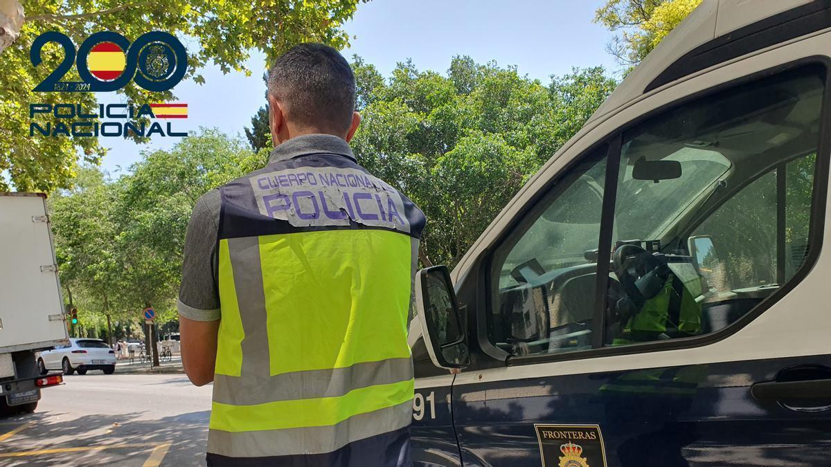 Un agente de la UCRIf de la Policía Naciional junto a su coche patrulla.