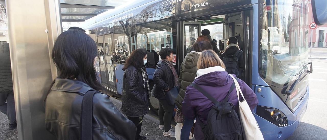 Gent esperant l'autobús en una parada del carrer Santa Eugènia.