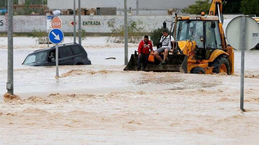 Dos ocupantes de un vehículo son rescatados con una pala mecánica, en Orihuela. // Efe