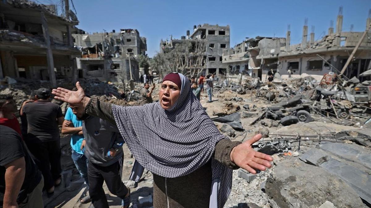 A Palestinian woman reacts as people assess the damage caused by Israeli air strikes  in Beit Hanun in the northern Gaza Strip  on May 14  2021  - Israel pounded Gaza and deployed extra troops to the border as Palestinians fired barrages of rockets back  with the death toll in the enclave on the fourth day of conflict climbing to over 100  (Photo by MAHMUD HAMS   AFP)