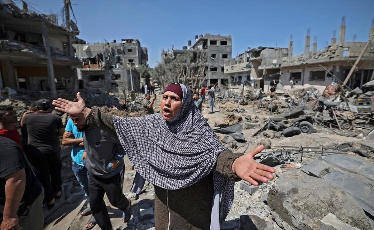 Una mujer palestina gesticula mientras un grupo de gente observa los daños causados por un ataque aéreo israelí en Beit Hanun, en el norte de la Franja de Gaza.