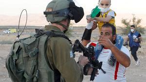 Un soldado israelí apunta con su arma al pecho de un palestino con su hijo en una protesta el martes contra el plan de anexión de Cisjordania.