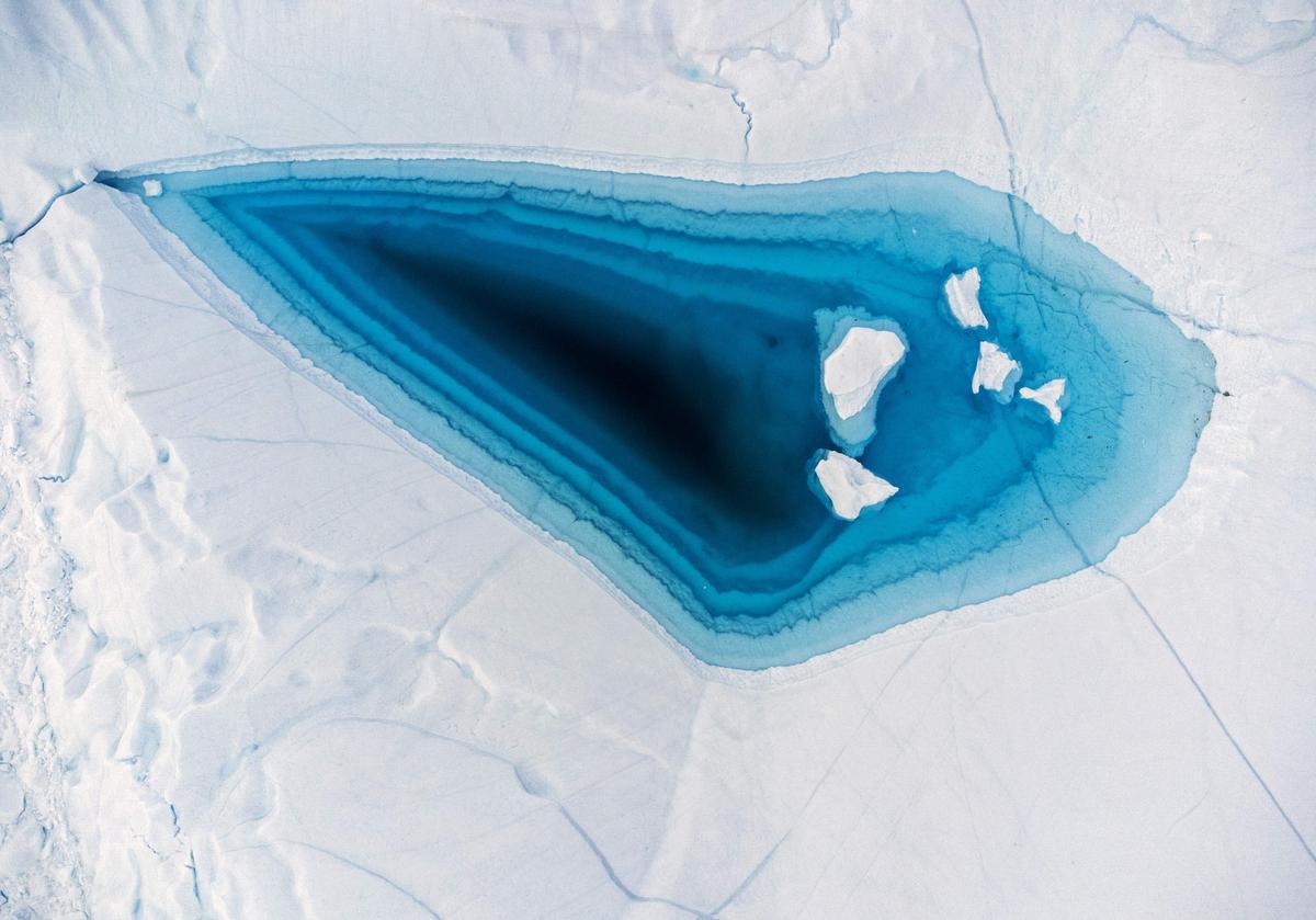 Agua turquesa se aprecia en un extenso agujero causado por el deshielo en la parte superior de un iceberg en la bahía de Disko, en Ilulissat, en Groenlandia, el 29 de junio del 2022. 