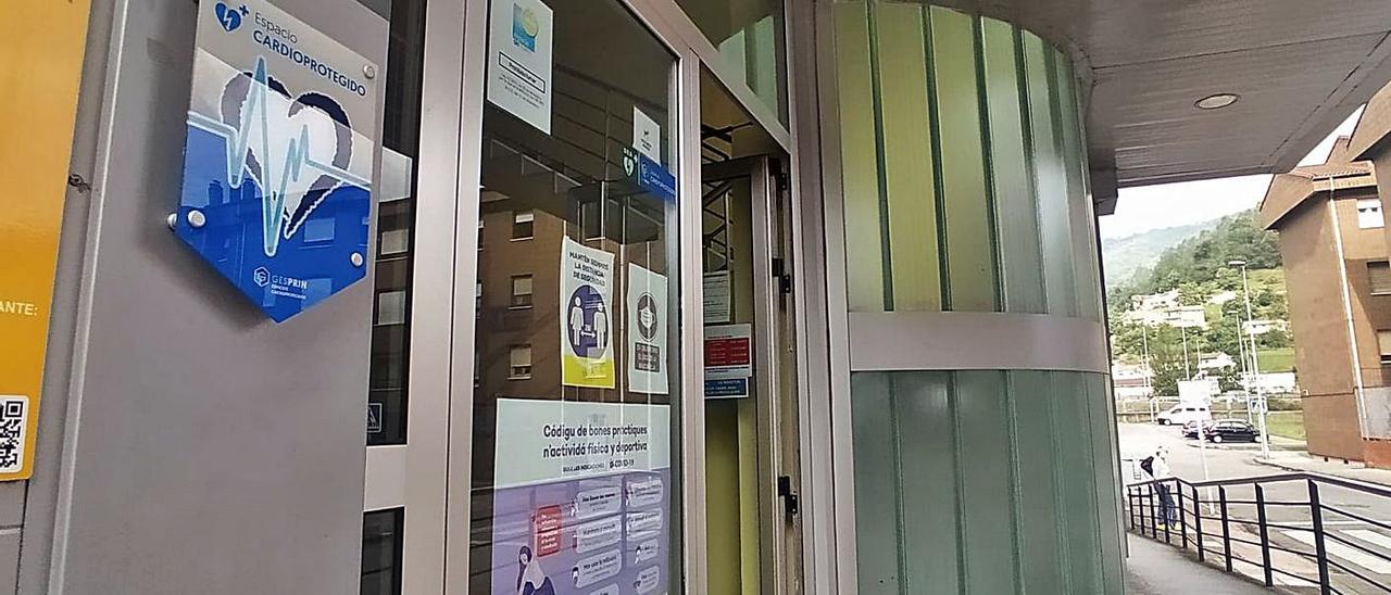 El acceso a la piscina municipal de Mieres, con el cartel que indica la presencia de desfribiladores. En el recuadro, Cristian Sánchez. | D. M.