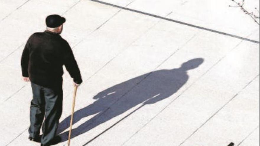 Imagen de un anciano observado su sombra en mitad de la calle.