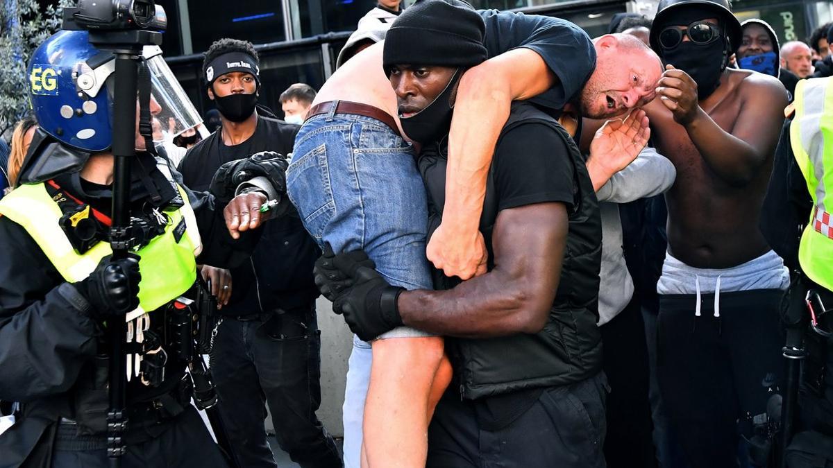 Patrick Hutchinson, con el manifestante blanco ultra herido al hombro, en Londres, el pasado sábado.