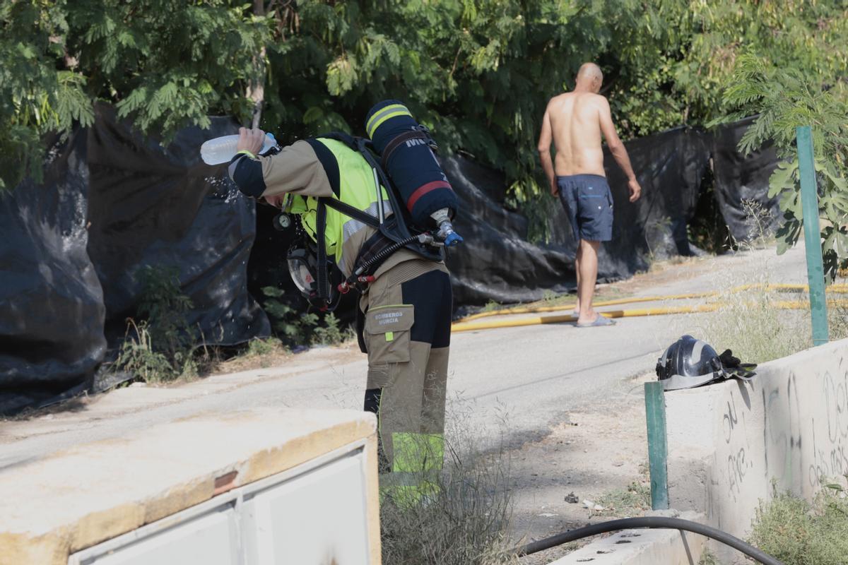 Un bombero se echa agua para refrescarse, este lunes en las labores de extinción del incendio del poblado chabolista en Murcia.