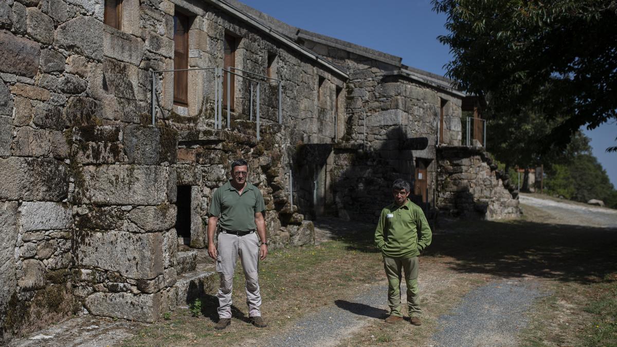 Los dos operarios que se ocupan del mantenimiento de la aldea, ante una de las viviendas restauradas. // BRAIS LORENZO