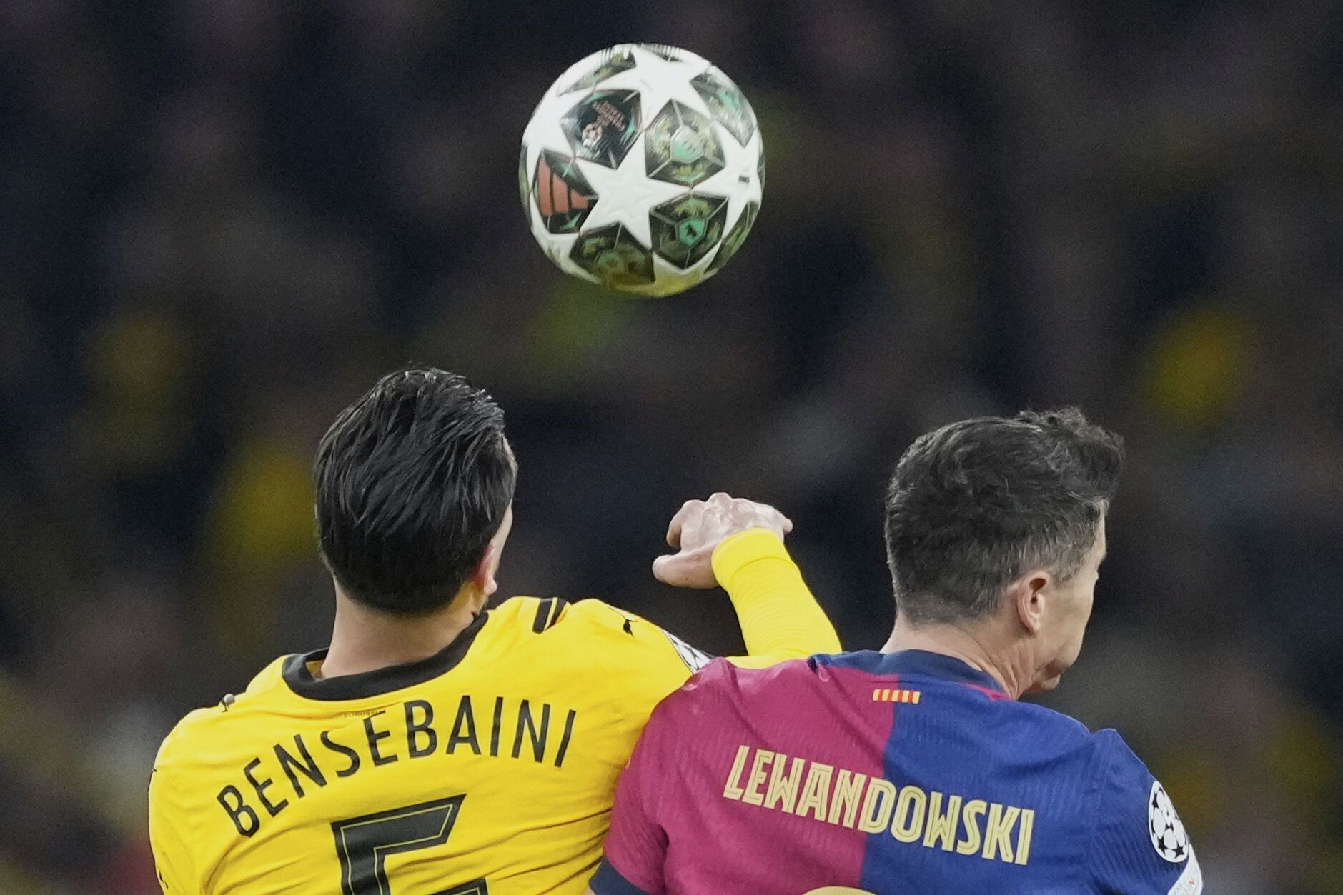 Dortmund's Ramy Bensebaini, left, duels for the ball with Barcelona's Robert Lewandowski during the Champions League quarterfinals second leg soccer match between Borussia Dortmund and Barcelona, at the Signa-Iduna Park in Dortmund, Germany, Tuesday, April 15, 2025. (AP Photo/Martin Meissner)