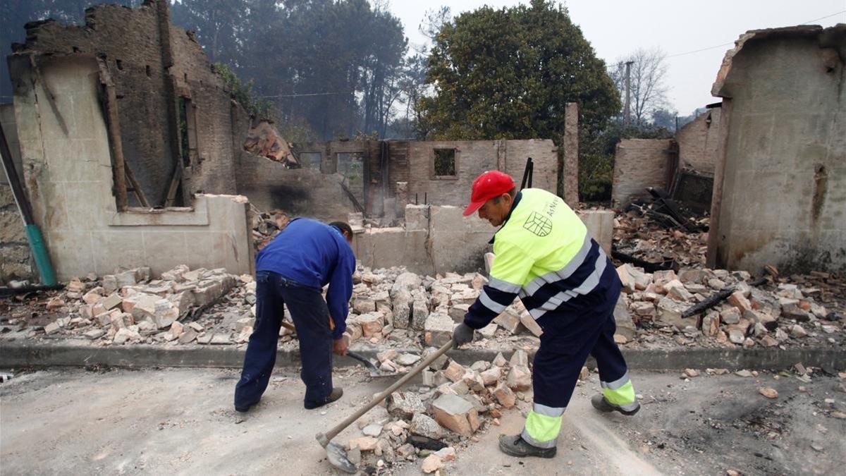 Dos operarios del concello pontevedrés de As Neves retiraban los cascotes de una casa derribada tras ser pasto del fuego.