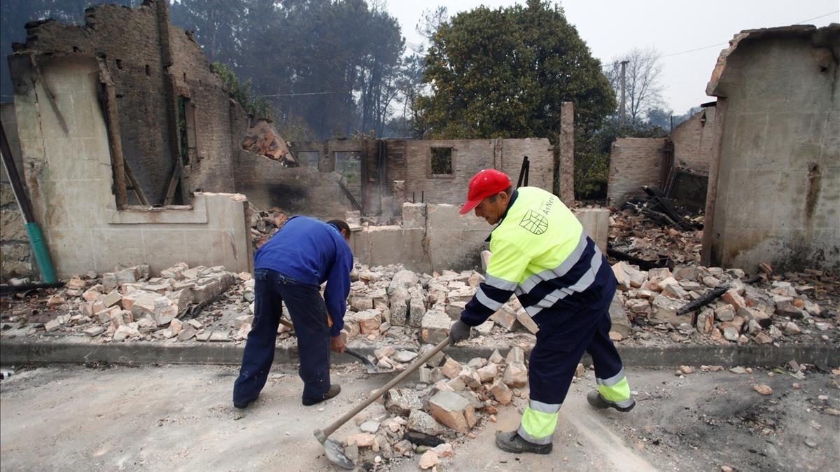 Dos operarios del concello pontevedrés de As Neves retiraban los cascotes de una casa derribada tras ser pasto del fuego.