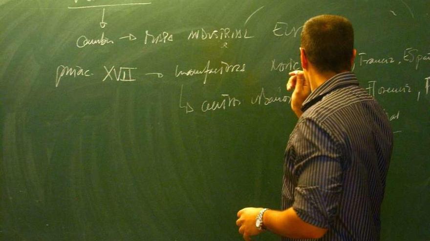 Un profesor escribe en la pizarra durante una clase.