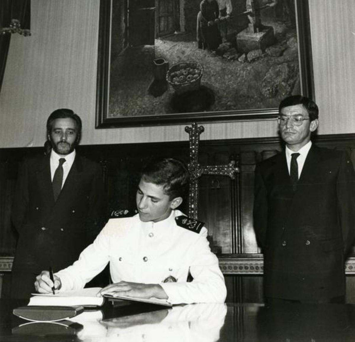 El entonces Príncipe de Asturias, firmando en el libro de oro de la comunidad, el día que recibió la Medalla de Asturias, el 20 de septiembre de 1986; tras él, Pedro de Silva y Juan Ramón Zapico.