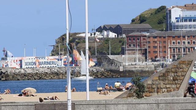 Al fondo, a la izquierda, el mural en la punta de Lequerica, con el edificio Torreón a la derecha, al principio del rompeolas, con la playa de Poniente en primer término.