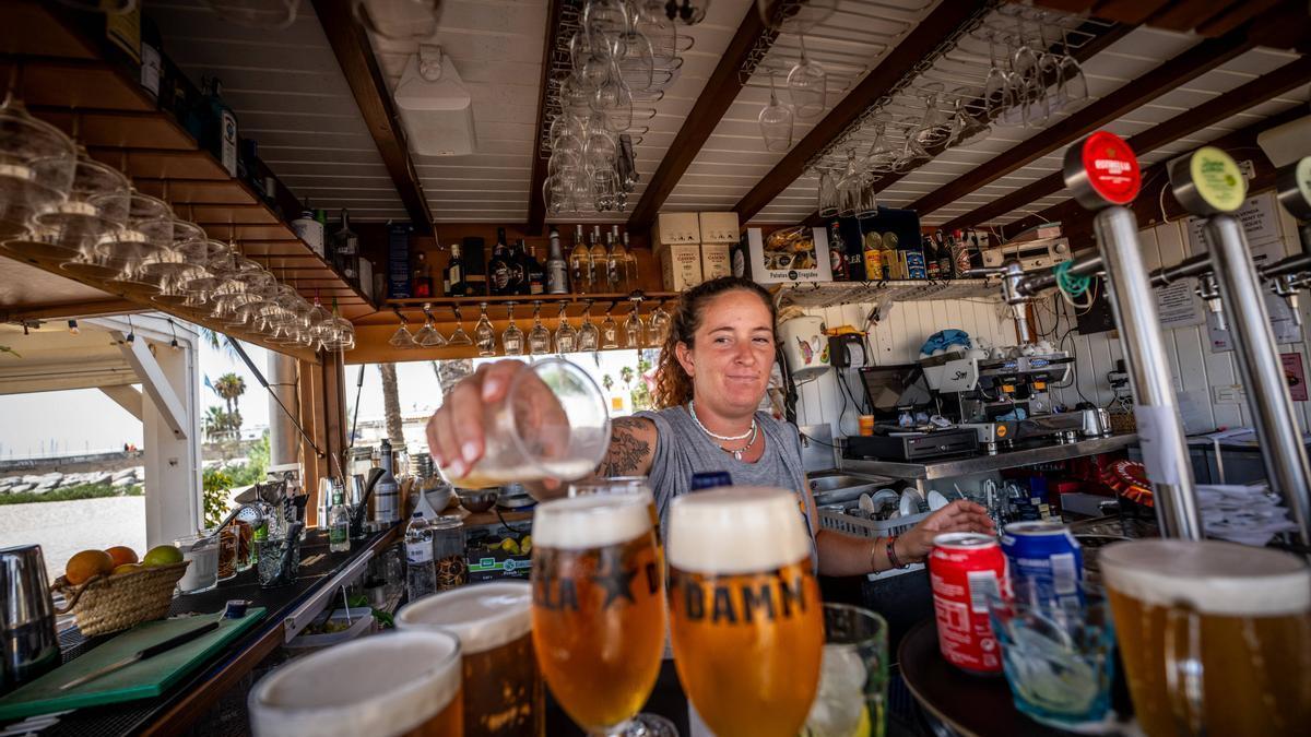 Una camarera prepara unas cervezas en un chiringuito de la playa de Mataró.