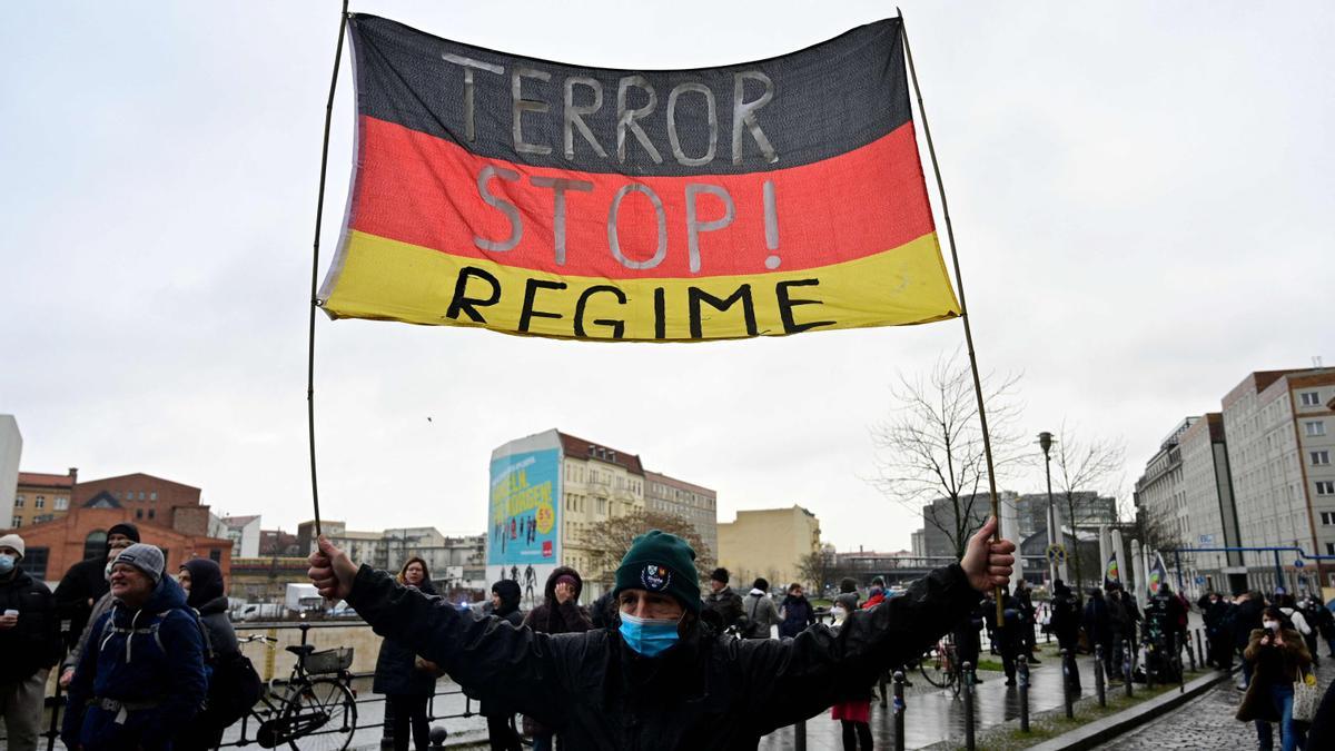 Un manifestante antivacunas muestra una bandera alemana en la que se puede leer &quot;Stop al régimen de terror&quot; durante una protesta en Berlín, el pasado 26 de enero.