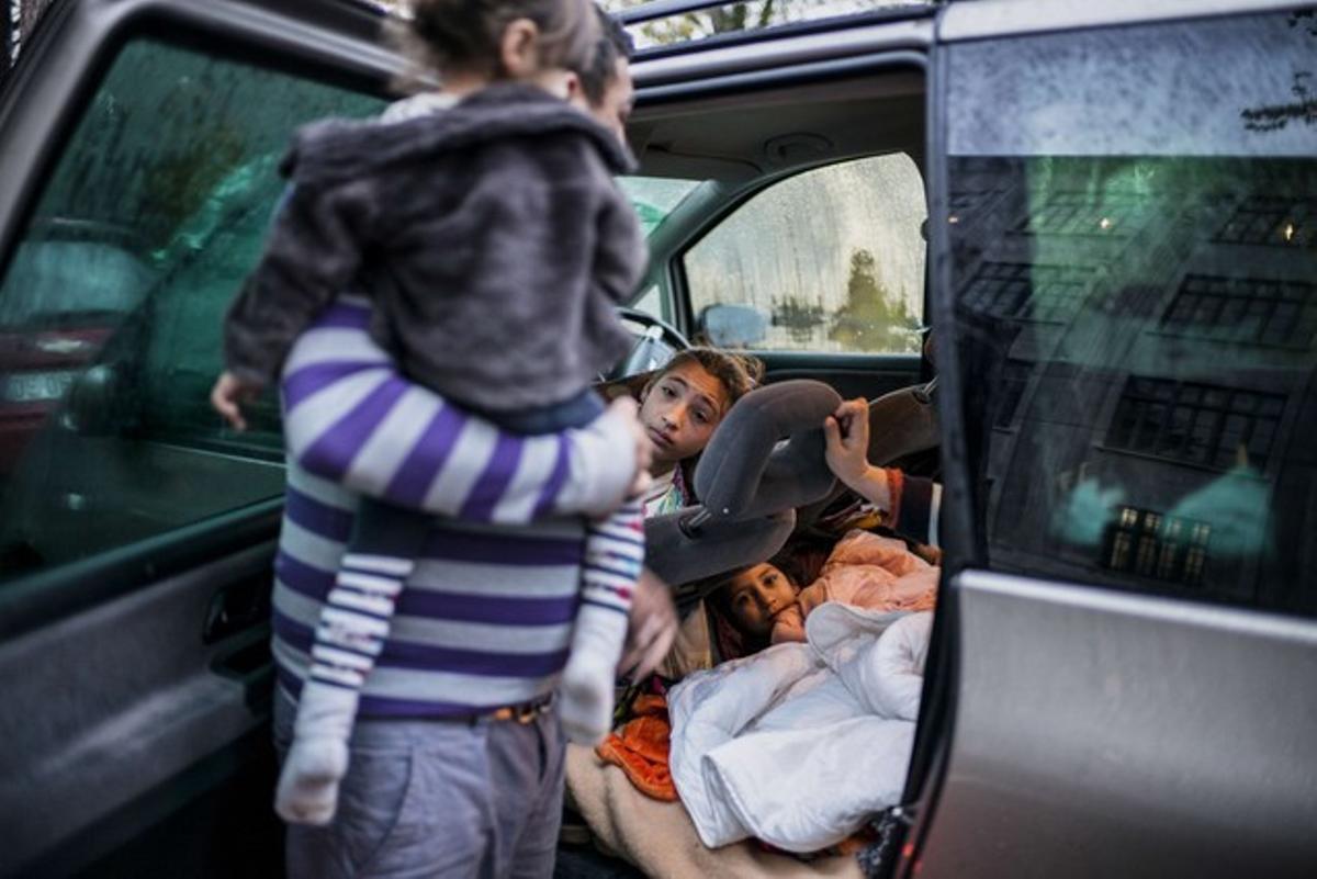 Miembros de varias familias sin hogar regresan a sus coches tras pasar la noche en una escuela ocupada en Lyon.