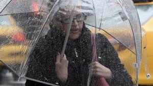Una mujer pasea con un paraguas bajo la lluvia.