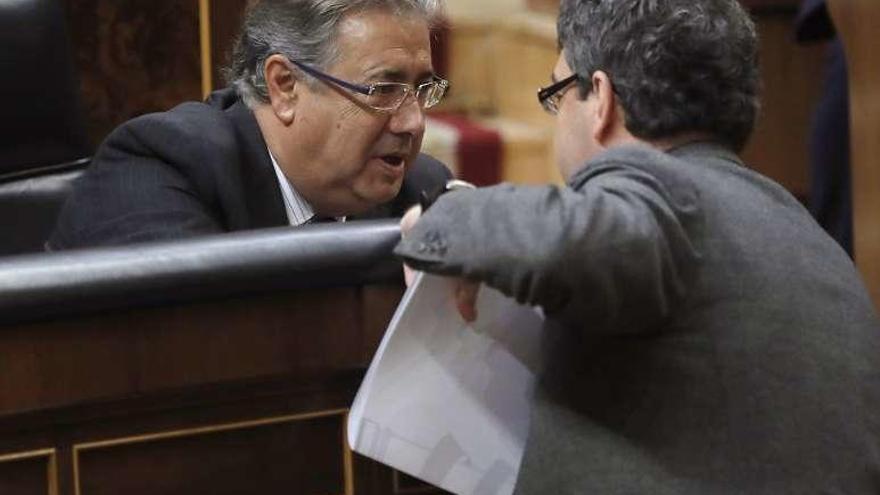 El ministro de Interior, Juan ignacio Zoido (sentado), conversa con el titular de Energía, Álvaro Nadal, en el Congreso. // Efe
