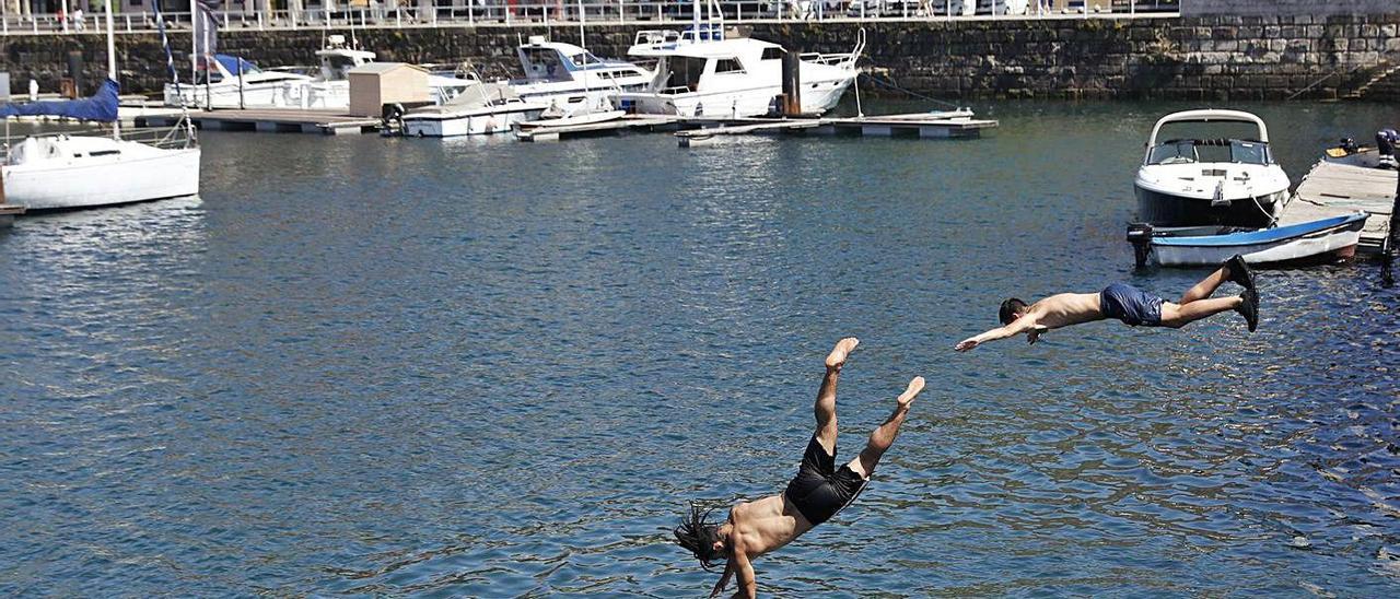 Dos jóvenes se lanzan al agua en el puerto deportivo, ayer.