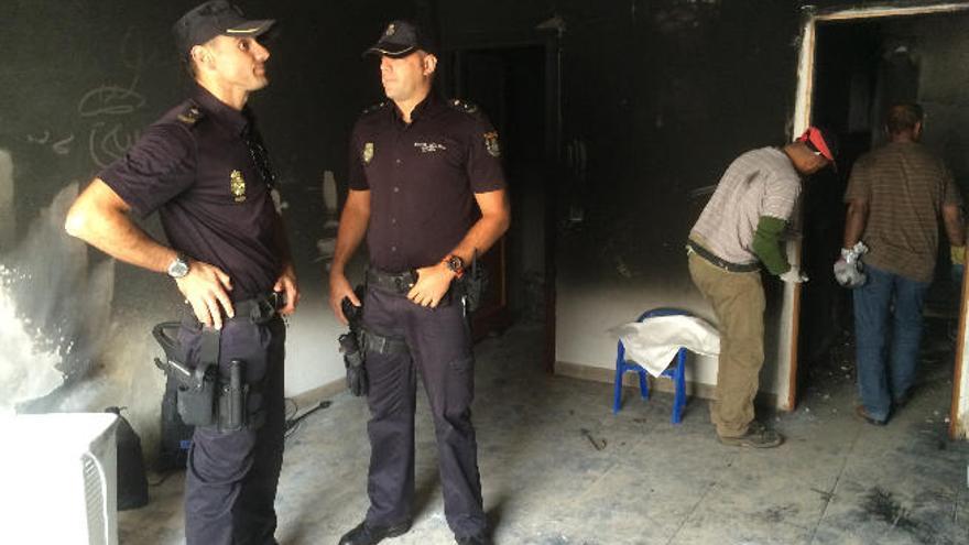 Los policías nacionales David y Ronald, ayer, en el salón de la vivienda en la que se originó el fuego.