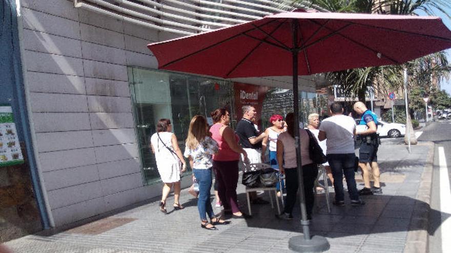 Un grupo de clientes de iDental, ayer junto a un policía.