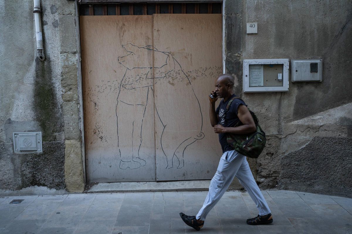 Un vecino de Vic pasea frente a un dibujo de un grafitti de un hombre y un cerdo.