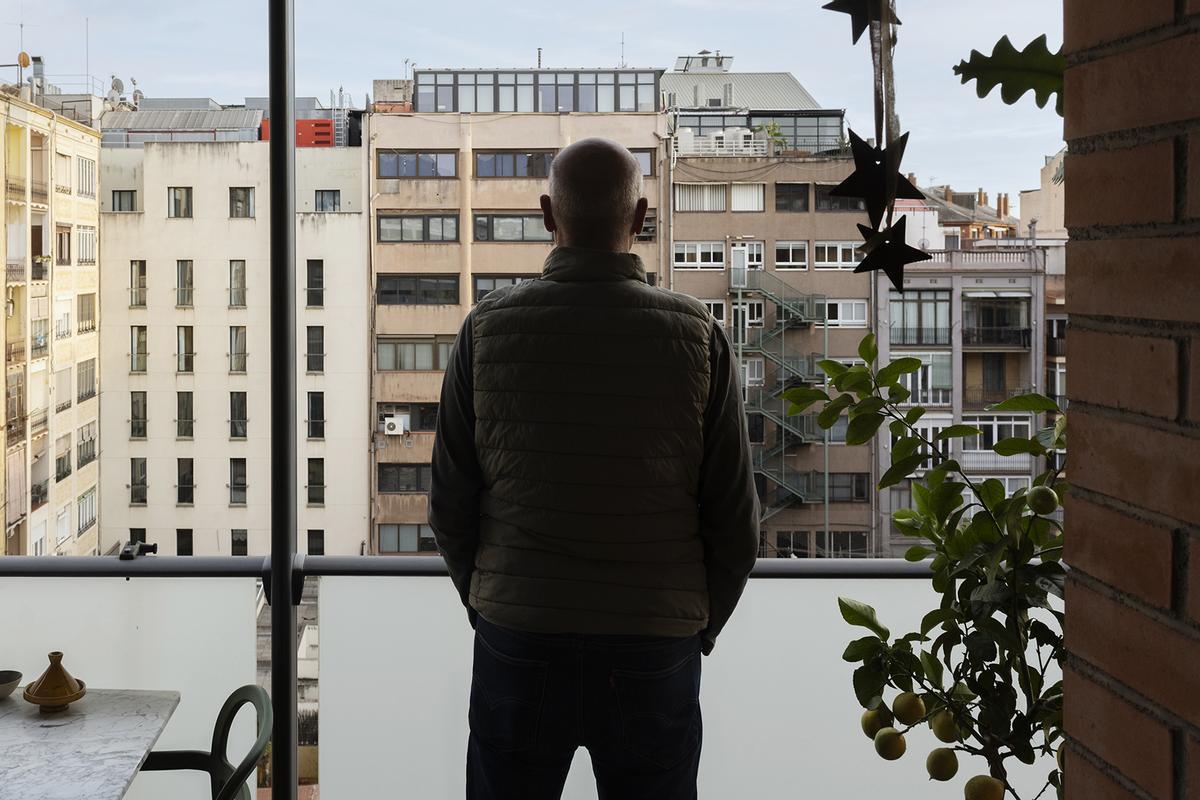 Un vecino, en la galería de su finca, con vista la fachada posterior de otros edificios.