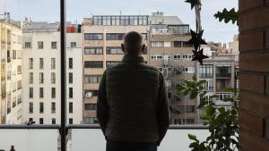 Un vecino, en la galería de su finca, con vista la fachada posterior de otros edificios.