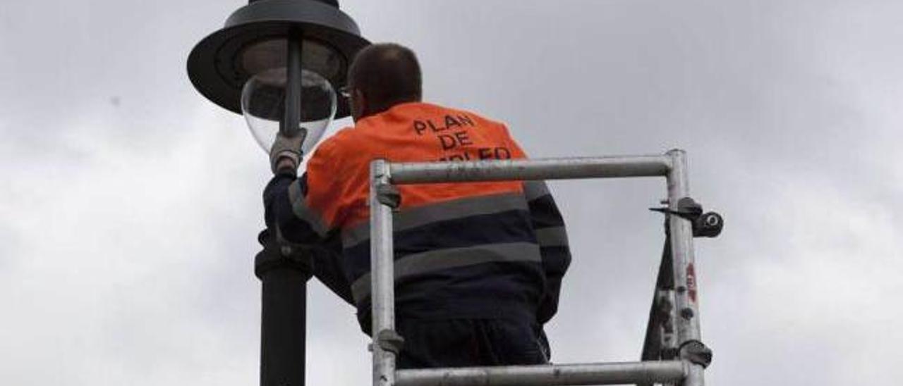 Un operario coloca una luminaria de bajo consumo en una farola en La Felguera.