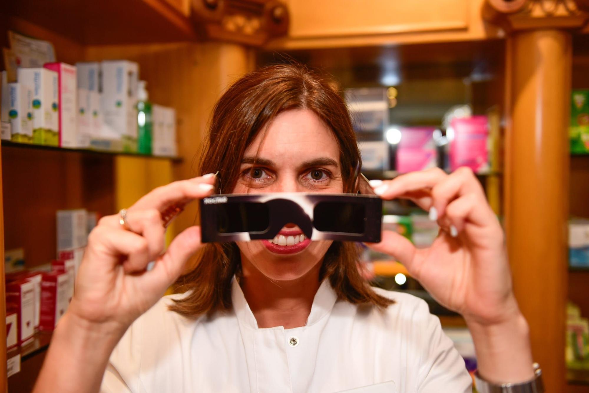 Beatriz Castelo, vocal de Óptica del Colegio Oficial de Farmacéuticos de A Coruña, sostiene unas gafas homologadas para mirar el eclipse solar, este lunes, en su farmacia de la Cuesta de la Tapia, en O Temple.
