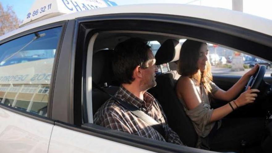 Una joven, conduciendo un coche de una autoescuela.  // G. Santos