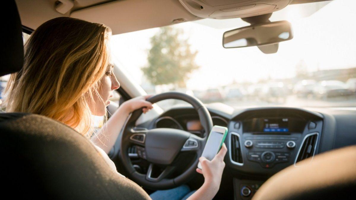 Una conductora escribe un mensaje con el móvil mientras conduce.
